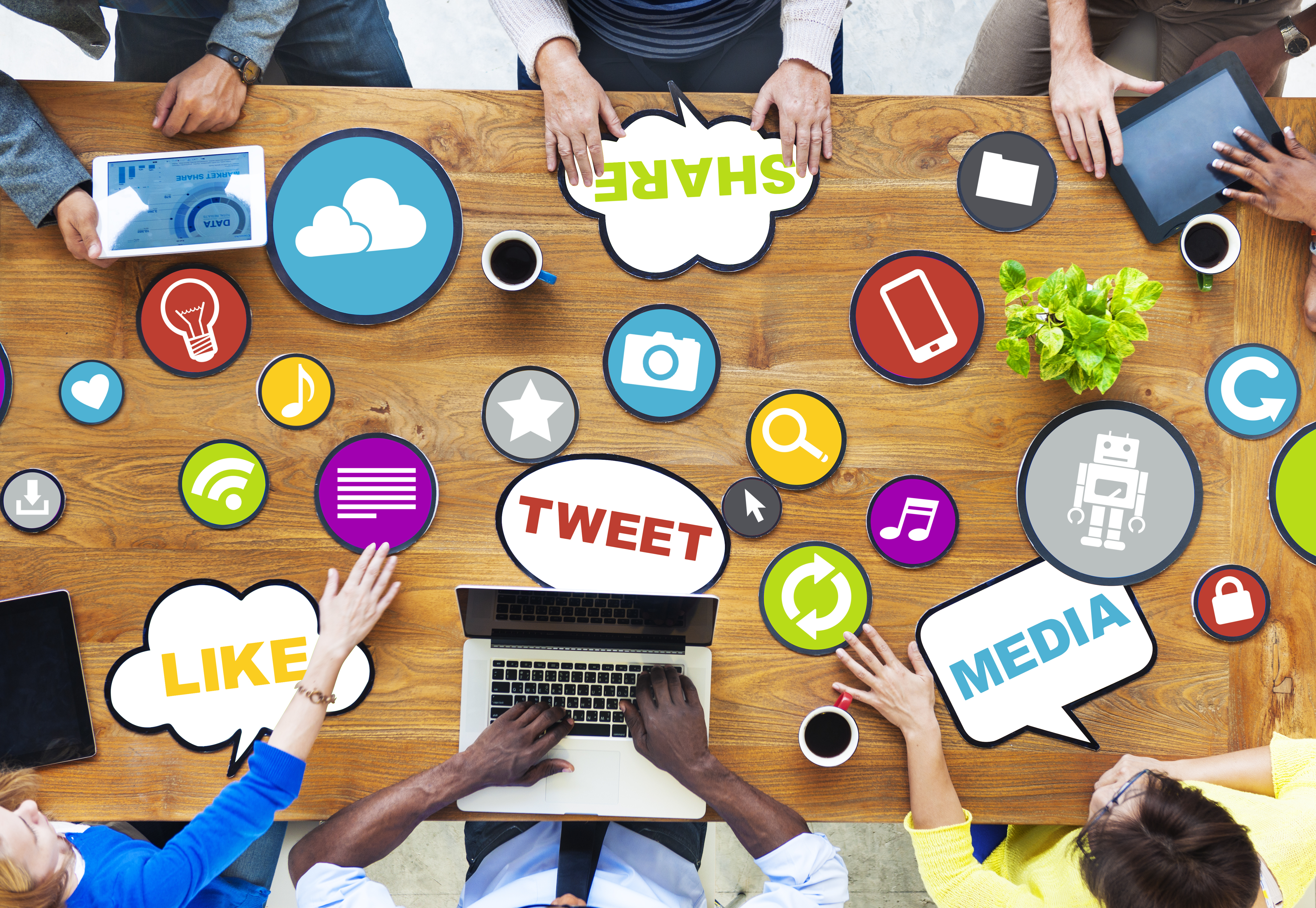 multiple people sitting together with social media keywords written all across the top of the table they are sitting at